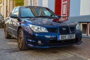 Carro Subaru Impreza azul com rodas douradas na rua