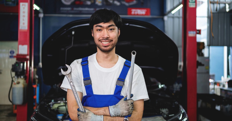 Profissional sorridente de macacão azul em oficina especializada de Subaru